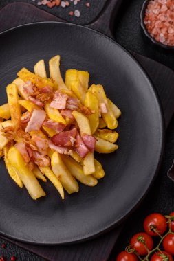Koyu beton arka planda domuz pastırması, tuz ve baharatla kızarmış patates kızartması.