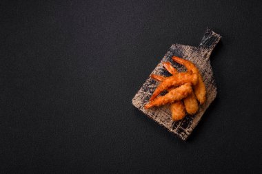 Sıcak gevrek karides, tuzlu ve baharatlı ve beyaz soslu, koyu beton arka planda.