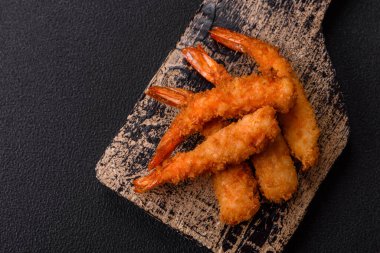 Sıcak gevrek karides, tuzlu ve baharatlı ve beyaz soslu, koyu beton arka planda.