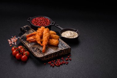 Sıcak gevrek karides, tuzlu ve baharatlı ve beyaz soslu, koyu beton arka planda.