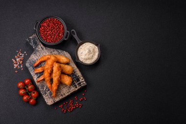 Sıcak gevrek karides, tuzlu ve baharatlı ve beyaz soslu, koyu beton arka planda.