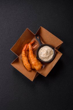 Sıcak gevrek karides, tuzlu ve baharatlı ve beyaz soslu, koyu beton arka planda.