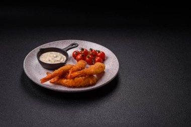 Sıcak gevrek karides, tuzlu ve baharatlı ve beyaz soslu, koyu beton arka planda.