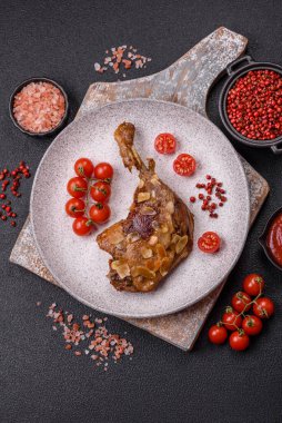 Koyu beton arka planda elma ve sos ile pişirilmiş ördek bacağı.