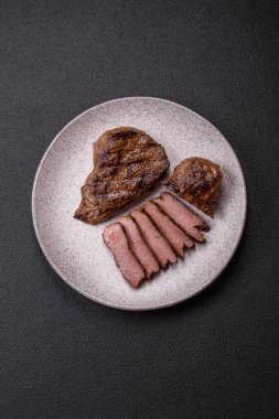 Tuz, baharat ve otlarla kaplanmış, koyu dokulu ızgara biftek.