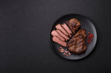 Tuz, baharat ve otlarla kaplanmış, koyu dokulu ızgara biftek.