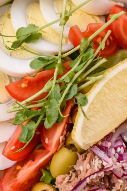 Ton balıklı salata, haşlanmış yumurta, vişneli domates, marul, tuz, baharat ve mikroyeşillik.