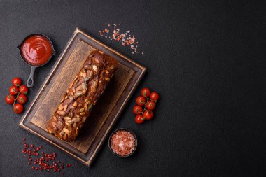 Koyu bir zeminde tohumlu, taneli, tuzlu ve baharatlı kahverengi ekmek.