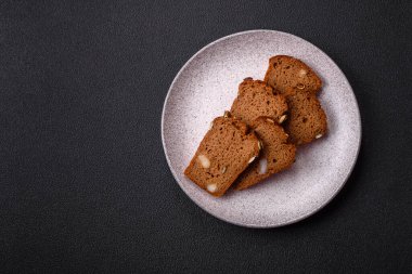 Koyu bir zeminde tohumlu, taneli, tuzlu ve baharatlı kahverengi ekmek.