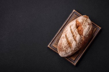 Koyu bir zeminde tohumlu, taneli, tuzlu ve baharatlı kahverengi ekmek.