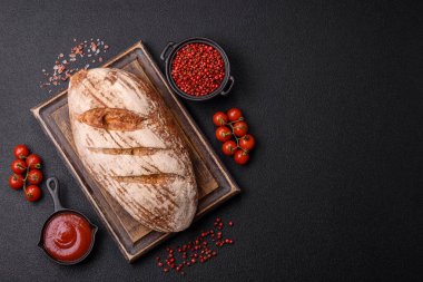 Koyu bir zeminde tohumlu, taneli, tuzlu ve baharatlı kahverengi ekmek.