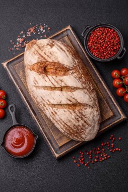 Koyu bir zeminde tohumlu, taneli, tuzlu ve baharatlı kahverengi ekmek.