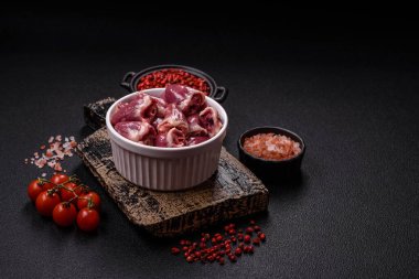 Raw chicken hearts with salt, spices and herbs on a dark concrete background clipart