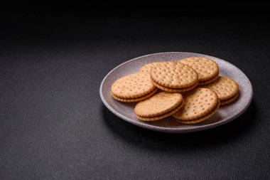 Koyu beton arka planda kremalı yuvarlak atıştırmalık kurabiyeler. Kahvaltıda tatlı.