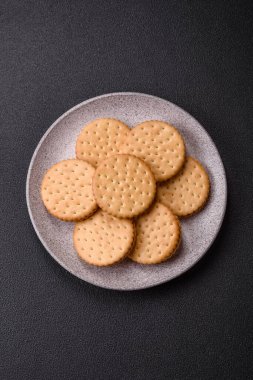 Koyu beton arka planda kremalı yuvarlak atıştırmalık kurabiyeler. Kahvaltıda tatlı.