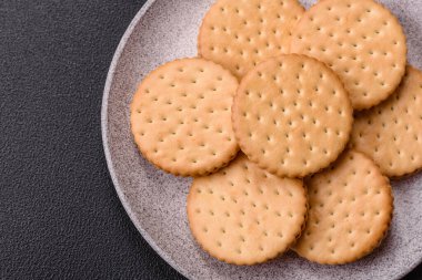 Koyu beton arka planda kremalı yuvarlak atıştırmalık kurabiyeler. Kahvaltıda tatlı.