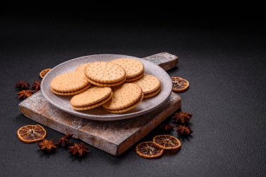 Koyu beton arka planda kremalı yuvarlak atıştırmalık kurabiyeler. Kahvaltıda tatlı.