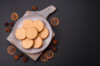 Koyu beton arka planda kremalı yuvarlak atıştırmalık kurabiyeler. Kahvaltıda tatlı.
