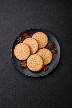 Koyu beton arka planda kremalı yuvarlak atıştırmalık kurabiyeler. Kahvaltıda tatlı.