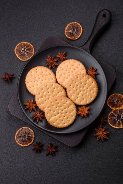 Koyu beton arka planda kremalı yuvarlak atıştırmalık kurabiyeler. Kahvaltıda tatlı.