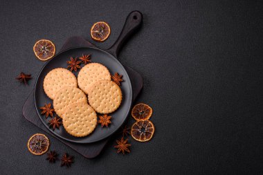 Koyu beton arka planda kremalı yuvarlak atıştırmalık kurabiyeler. Kahvaltıda tatlı.