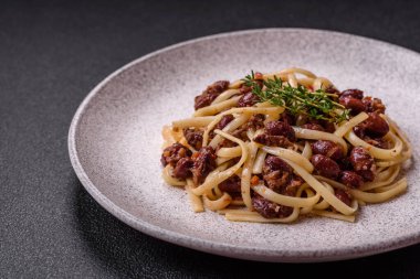 Fasulyeli erişte, et, domates sosu, baharatlar ve otlar koyu beton arka planda.