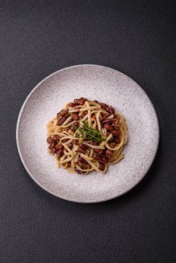 Fasulyeli erişte, et, domates sosu, baharatlar ve otlar koyu beton arka planda.