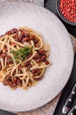 Fasulyeli erişte, et, domates sosu, baharatlar ve otlar koyu beton arka planda.