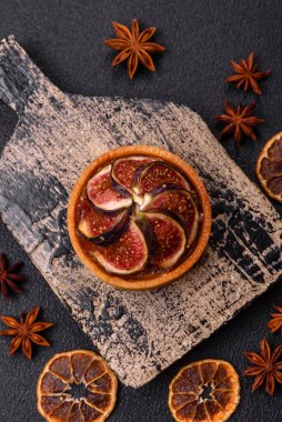 İncirli tatlı tart, peynirli krema ve fındıklı koyu beton arka plan