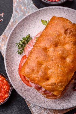 Salamlı, peynirli, domatesli roka, tuzlu, baharatlı ve çimento kaplı Focaccia.