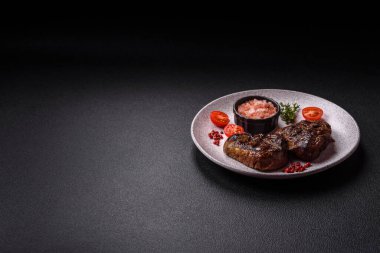 Izgarada pişirilmiş sulu biftek. Koyu beton arka planda tuz, baharat ve otlarla.