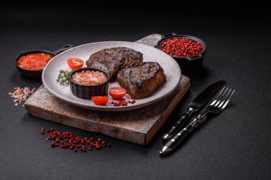 Izgarada pişirilmiş sulu biftek. Koyu beton arka planda tuz, baharat ve otlarla.