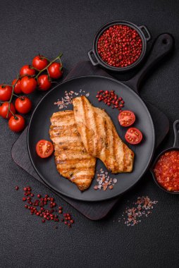 Izgarada pişirilmiş sulu tavuk filetosu. Koyu beton arka planda tuz, baharat ve otlarla birlikte.