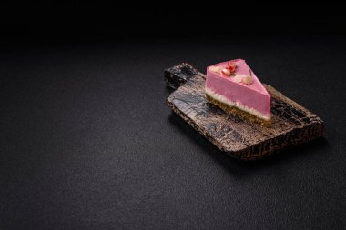Pembe krem peynirli, ahududu aromalı veya koyu dokulu arkaplanda çilekli tatlı cheesecake.