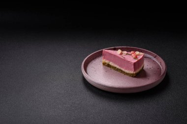 Pembe krem peynirli, ahududu aromalı veya koyu dokulu arkaplanda çilekli tatlı cheesecake.