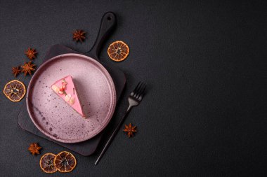 Pembe krem peynirli, ahududu aromalı veya koyu dokulu arkaplanda çilekli tatlı cheesecake.