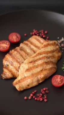 Izgarada pişirilmiş sulu tavuk filetosu. Koyu beton arka planda tuz, baharat ve otlarla birlikte.