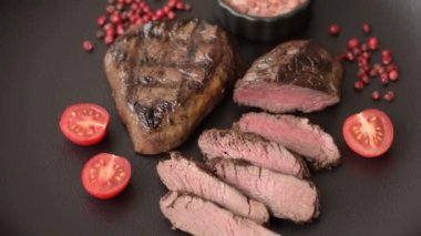 Izgarada pişirilmiş sulu biftek. Koyu beton arka planda tuz, baharat ve otlarla.