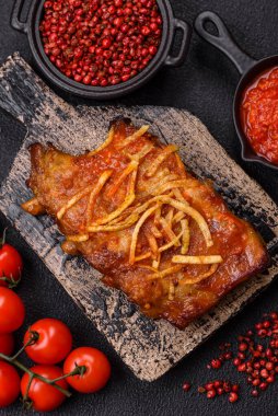 Koyu beton bir arka planda ızgarada pişirilmiş tuzlu, baharatlı ve otlu domuz ya da biftek kaburgası.