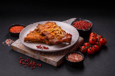 Koyu beton bir arka planda ızgarada pişirilmiş tuzlu, baharatlı ve otlu domuz ya da biftek kaburgası.