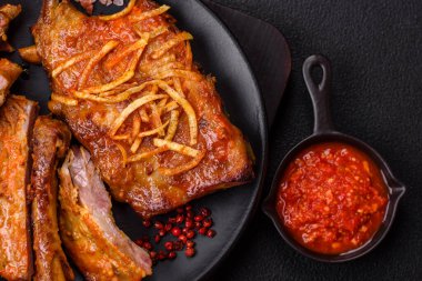 Koyu beton bir arka planda ızgarada pişirilmiş tuzlu, baharatlı ve otlu domuz ya da biftek kaburgası.