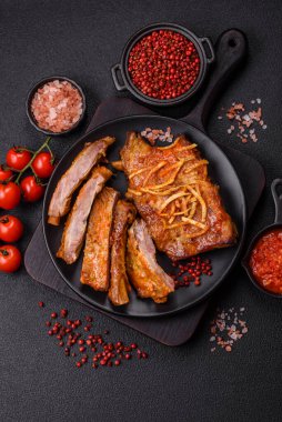 Koyu beton bir arka planda ızgarada pişirilmiş tuzlu, baharatlı ve otlu domuz ya da biftek kaburgası.