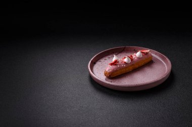 Koyu dokulu arka planda çilekli kremalı tatlı ekler veya profiterol.