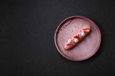 Koyu dokulu arka planda çilekli kremalı tatlı ekler veya profiterol.