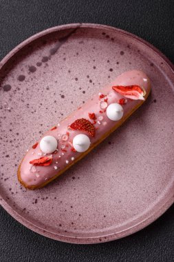 Koyu dokulu arka planda çilekli kremalı tatlı ekler veya profiterol.