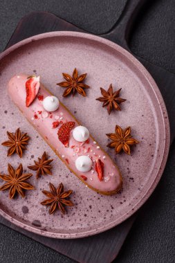 Koyu dokulu arka planda çilekli kremalı tatlı ekler veya profiterol.