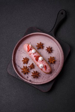 Koyu dokulu arka planda çilekli kremalı tatlı ekler veya profiterol.