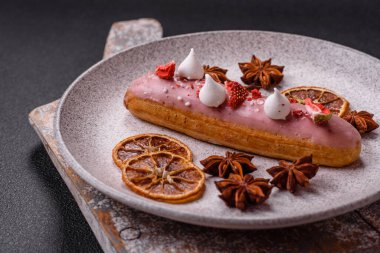 Koyu dokulu arka planda çilekli kremalı tatlı ekler veya profiterol.