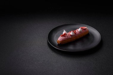 Koyu dokulu arka planda çilekli kremalı tatlı ekler veya profiterol.