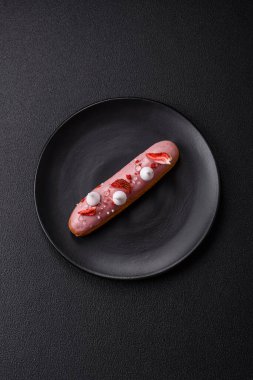 Koyu dokulu arka planda çilekli kremalı tatlı ekler veya profiterol.